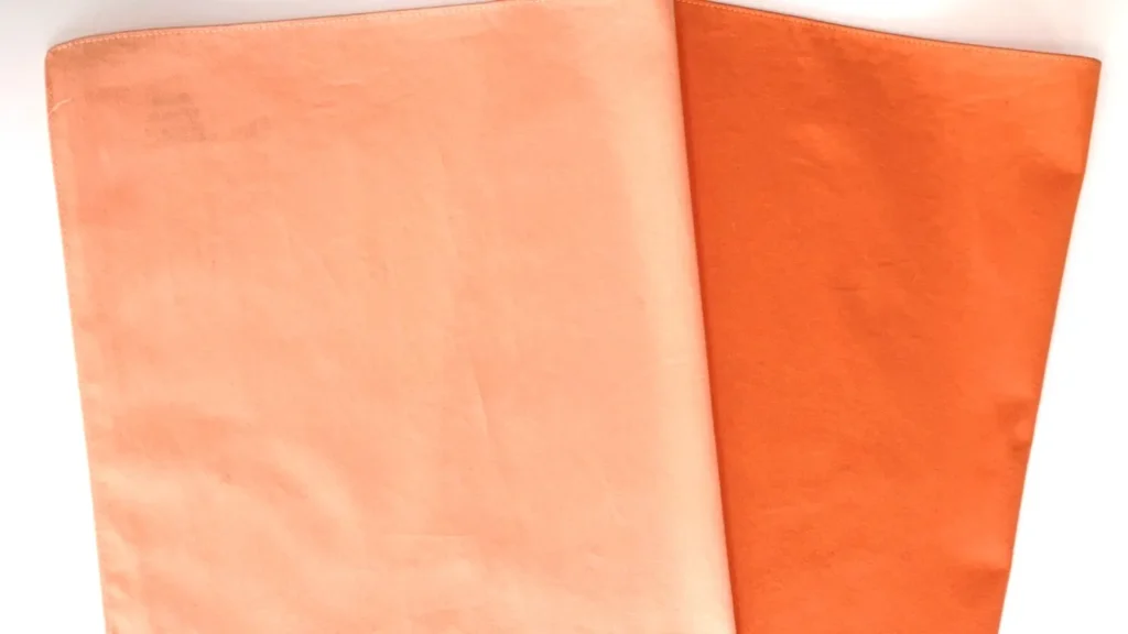 鮮やかなオレンジの布と、パステル調の淡いコーラルピンクの布を並べた比較画像